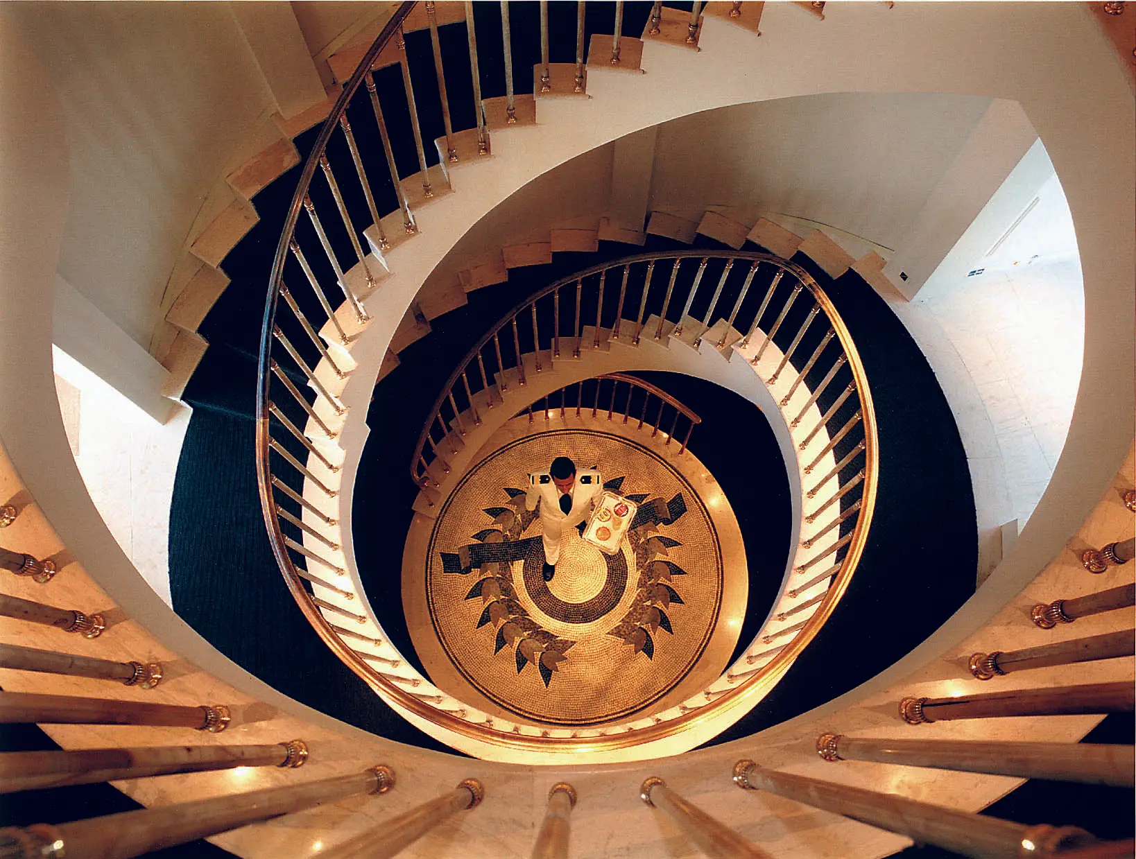 Spiral staircase aboard CHRISTINA O with marble steps and a mosaic floor below