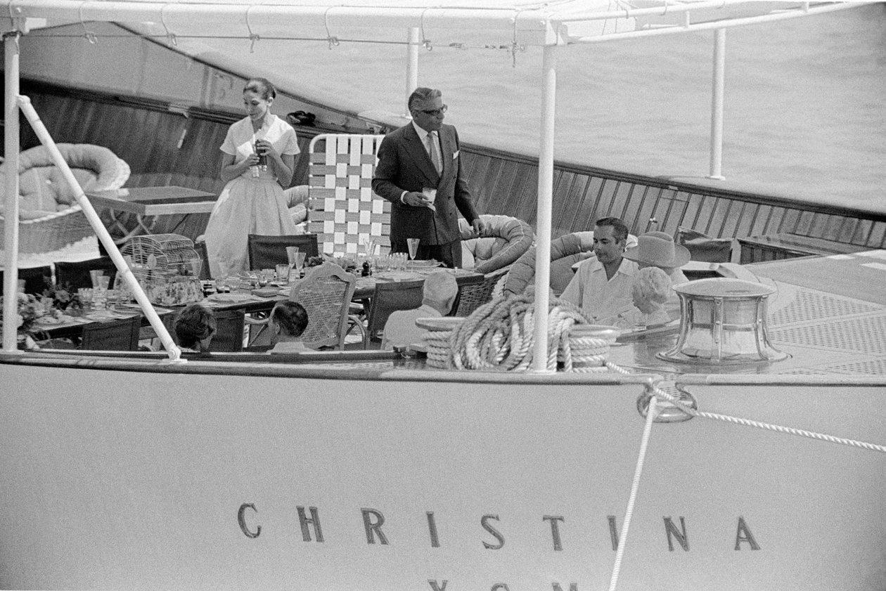 Onassis serving drinks to guests at a table on the aft deck of CHRISTINA